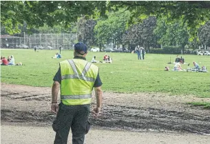  ?? CHRIS YOUNG THE CANADIAN PRESS ?? A city bylaw enforcer looks on as people sit within circles in Toronto’s Trinity Bellwoods Park. Two-thirds of the charges and three-quarters of the fines were given out in Quebec.