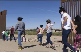  ?? EUGENE GARCIA — THE ASSOCIATED PRESS ?? A group of migrants make their way around a gap in the U.S.-Mexico border in Yuma, Ariz., in 2021. The Biden administra­tion has unveiled new procedures that empower asylum officers to grant or deny claims, an authority that has been limited to immigratio­n judges for people arriving at the border with Mexico.