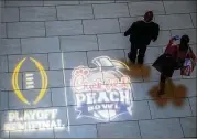  ?? STEVE SCHAEFER / SPECIAL TO THE AJC ?? People walk by the Chick-fil-A Peach Bowl logo on the floor of the Hyatt Regency Atlanta on Thursday.