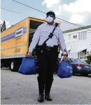  ?? Miami Herald Staff ?? Miami Beach Police Officer Alvarez helps deliver food to residents in need in North Beach.