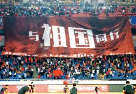  ??  ?? Fans hold a giant banner that reads “go with the motherland” at a match between Chongqing Football Club and Jiangsu Football Club, September 2019