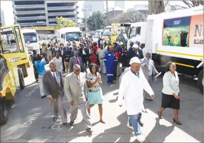  ?? — Picture by John Manzongo ?? Harare Mayor Councillor Bernard Manyenyeni (in white dustcoat), Acting Town Clerk Ms Josephine Ncube (right) and other officials inspect the new fleet of refuse compactors and trucks at Town House yesterday.