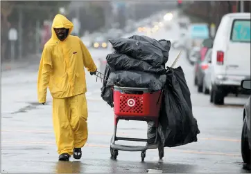  ?? JANE TYSKA — STAFF PHOTOGRAPH­ER ?? A man pulls a shopping cart along Adeline Street in the rain in Oakland on Wednesday. Another storm is expected Friday.