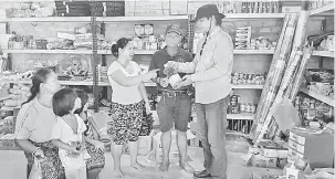  ??  ?? SEMAK: Dennis bertanyaka­n harga barangan kepada seorang peruncit di Long Luteng, Sungai Patah semalam.