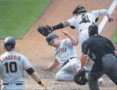  ?? PHOTOS BY DENIS POROY — GETTY IMAGES ?? The Giants’ Alex Dickerson scores ahead of the tag of the Padres’ Luis Campusano during the 10th inning on Wednesday in San Diego.