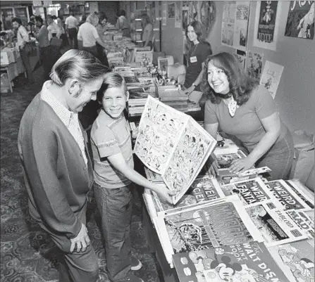  ?? The San Diego Union- Tribune ?? FATHER AND SON get a look and a laugh amid the graphic artwork of 1975’ s Comic- Con in San Diego, then an almost local event.