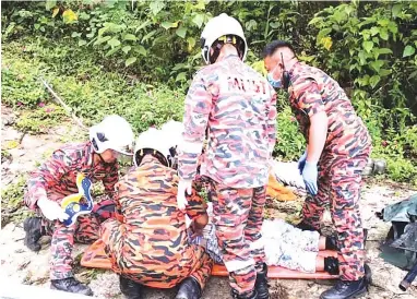  ??  ?? Fire and Rescue personnel attending to the only victim who survived the crash at a road bend near Kampung Bundu Tuhan.