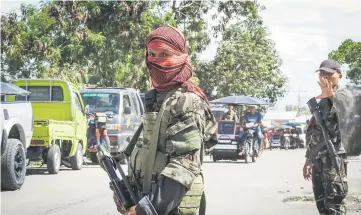  ??  ?? Photo shows a Moro Islamic Liberation Front (MILF) rebel (left) with face covered, along with a government soldier (right) manning a mobile check point in Datu Salibo town, Maguindana­o province, in southern island of Mindanao. — AFP photo