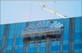  ??  ?? A work crew removes the Mandarin Oriental fan from the top of what is now the Waldorf Astoria.