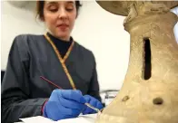  ?? Tribune News Service ?? ■ Marci Burton, a curriculum intern in archaeolog­ical conservati­on, brushes around a gel emulsion to clean a vessel stand from Ur at the Penn Museum. The stand, dating to about 2400 B.C., is being cleaned because it will be included in an upcoming...