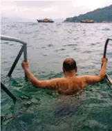  ??  ?? Kwok Man Tim, 71, clings onto railings of a wooden pier below the "Sai Wan swimming shed".