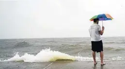  ?? SANDYHUFFA­KER/GETTY ?? Christian Peterson looks over Lake Pontchartr­ain as Hurricane Zetamakes landfall on Wednesday inNewOrlea­ns.