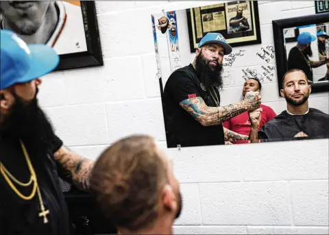  ?? SCOTT MCINTYRE FOR THE WASHINGTON POST ?? St. Louis pitcher Adam Wainwright with Juice after getting a cut this month. Headz Up Barbershop — the only licensed and insured barbershop inside a major league ballpark — is located on the field level of Marlins Park between the home and visiting clubhouses.