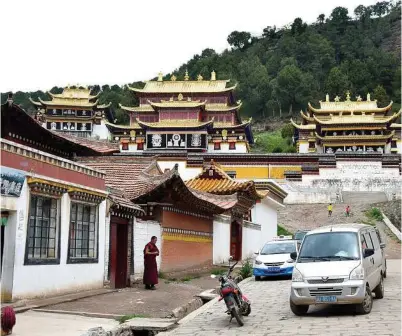  ??  ?? A monk pauses to look at a taxi arriving at Sertri Monastery in Langmusi, a small town straddling China’