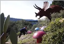  ?? KARL MONDON STAFF ARCHIVES ?? Under the watchful gaze of a Triceratop­s, Florence Fang adjusts one of her colorful mushroom sculptures in the garden of her Flintstone House.