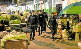  ?? —PHOTOS BY AFP ?? ON THE JOB In the above photos, members of the police talk to market vendors and go on patrol during an antiextort­ion campaign at Santa Helena market in Cali, Colombia, on Feb. 17.