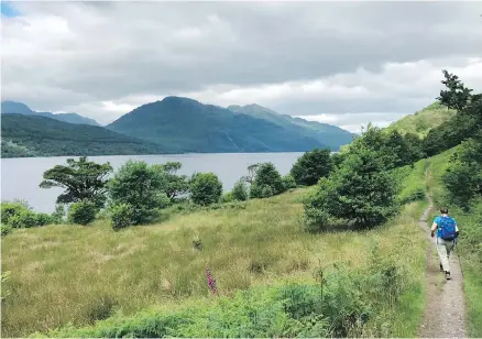  ??  ?? A hiker passes by Loch Lomond on the West Highland Way, Scotland’s oldest long-distance path. Loch Lomond, the largest inland stretch of water in Great Britain by surface area, is in Trossachs National Park.