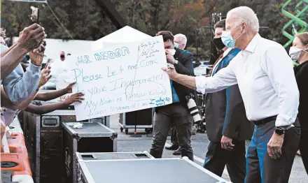  ?? ERIN SCHAFF/THE NEW YORK TIMES ?? Joe Biden hands a sign to Braylon Edwards, 10, Tuesday in Atlanta. Edwards asked to attend Biden’s presidenti­al inaugurati­on in January if he’s elected.