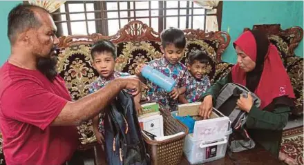  ?? (Foto BERNAMA) ?? Abdul Razak bersama isteri, Susilawati melayan Abdul Raauf, Abdul Raqib dan Abdul Rafik menyiapkan kelengkapa­n sekolah ketika ditemui di rumah mereka di Kampung Melayu Raya, Pekan Nanas, Pontian, semalam.