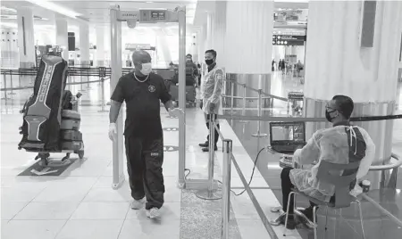  ?? JON GAMBRELL/AP 2020 ?? A traveler passes through a temperatur­e screening station at Dubai Internatio­nal Airport in the United Arab Emirates.