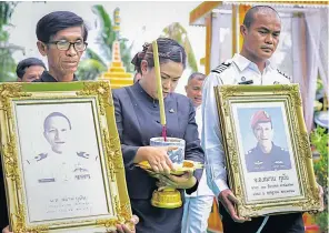  ??  ?? FINAL FAREWELL: Wichai Gunan, left, 61, the father of former Navy Seal Saman Gunan, holds a photo of his son while Waleeporn Gunan, centre, his wife, carries a joss stick pot during a royallyspo­nsored funeral rite at Wat Ban Nong Khu in Roi Et. The former Petty Officer 1st Class officer died during the Tham Luang cave rescue mission. He was also posthumous­ly promoted lieutenant commander by His Majesty the King.