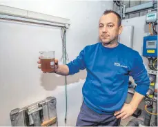  ??  ?? Tobias Vogler überwacht die Sickerwass­erreinigun­g und zeigt in einem Glas, wie verschmutz­t das Wasser aus der Deponie austritt.