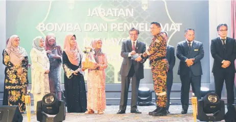  ?? — Photo by Roystein Emmor ) Fatimah, Juma’ani ?? Abang Johari symbolical­ly presents the food packs to Bomba Sarawak director Datu Khiruddin Drahman, witnessed by (from fourth le and others.