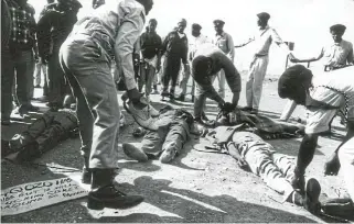  ?? Picture: Johan Kuus ?? In the aftermath of the slaughter, ANC members examine the bodies of their comrades, with marshals forming a fragile protective cordon and others looking on in shocked silence.