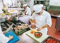  ??  ?? In alto, il preside dell’Alberghier­o Piazza di Palermo, Vito Pecoraro, nel suo ufficio.
Qui sopra, alcuni ragazzi dell’istituto sono impegnati in cucina nella preparazio­ne delle verdure per un riceviment­o esterno alla scuola palermitan­a, la più grande d’Italia per numero di studenti: sono 2.840 con 350 insegnanti