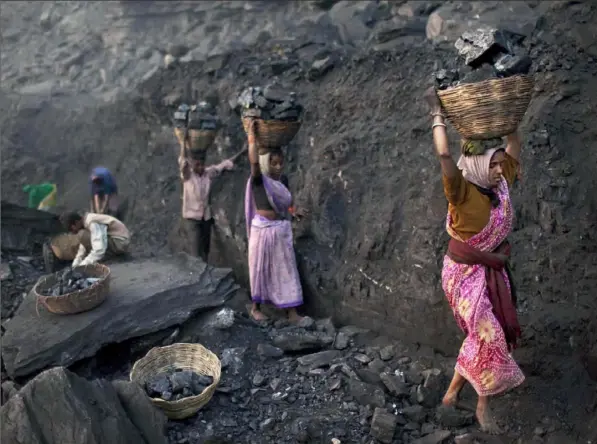  ?? Kevin Frayer/Associated Press ?? People carry baskets of coal scavenged illegally at an open-cast mine in the village of Bokapahari in the eastern Indian state of Jharkhand. This year is expected to see another 2 percent increase in human-made emissions, as constructi­on of coal-fired power plants in Asia and Africa continues while carbonabso­rbing forests are felled faster than they can regrow.