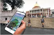  ?? CHARLES KRUPA/THE ASSOCIATED PRESS ?? A Pokémon Go player walks through the Boston Common, outside the Massachuse­tts Statehouse in Boston. Players hunting for fictional creatures on their smartphone­s are now visiting real-life memorial plaques, statues, mosaics and landmarks.