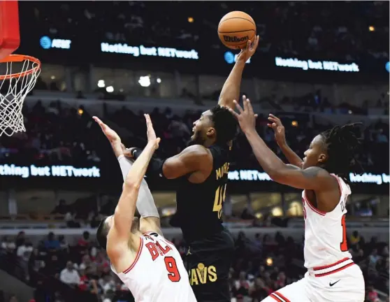  ?? PAUL BEATY/AP ?? The Cavaliers’ Donovan Mitchell goes up for a shot between Bulls defenders Nikola Vucevic (left) and Ayo Dosunmu in the first half Saturday at the United Center.