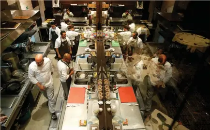  ?? (Ivan Alvarado/Reuters) ?? CHEF CARLOS GARCIA (left) and his crew work in the kitchen of the Alto restaurant in Caracas last month. To weather shortages, Garcia travels deep into Venezuela for supplies for Alto, the only Venezuelan business on the coveted 50 Best Latin American...