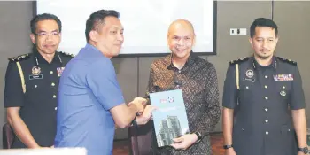  ?? ?? Armizan (second right) presenting a certificat­e to a representa­tive of an enforcemen­t department, witnessed by Azman (left) and Zulfamy (right).