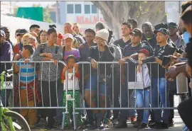 ?? Nelvin C. Cepeda San Diego Union-Tribune ?? MIGRANTS wait to cross the U.S.-Mexico border. A 9th Circuit panel ruled that border agents “have no general authority to search for crime” in phone searches.