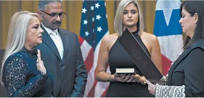  ?? DENNIS M. RIVERA PICHARDO/AP ?? Justice Secretary Wanda Vazquez is sworn in Wednesday as governor of Puerto Rico by the island’s Supreme Court Justice Maite Oronoz.