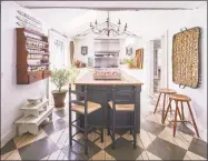  ?? Contribute­d photo ?? An antique-plank floor painted in a diamond pattern grounds the large butcher block island. Live greenery, a wooden spice rack, wicker accessorie­s and brushed metal lighting soften the space.