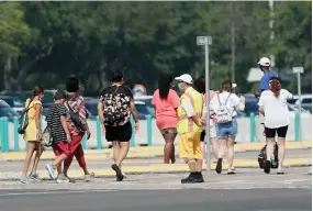  ?? AP PHOTO BY JOHN RAOUX ?? An attendant, front, directs park guests to the entrance of the Magic Kingdom during the reopening at Walt Disney World, Saturday, July 11, 2020, in Lake Buena Vista, Fla.