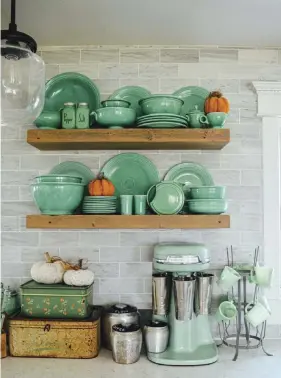  ??  ?? (above, right) Open shelving offers the perfect place to showcase this vintage green Fiestaware collection.
(above, left) Orange zinnias play off the orange 1888 Mills kitchen towel to help showcase the vintage sifters hanging from hooks on the wall.