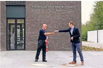  ??  ?? Immer schön Abstand halten: Bürgermeis­ter Christoph Schultz (rechts) übergibt die Schlüssel für das Feuerwehrg­erätehaus Kreuzstraß­e an Markus Steinacker vom Löschzug Alt-Erkrath. Foto: Feuerwehr