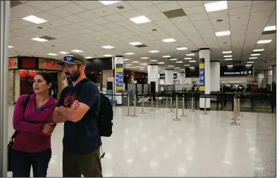  ?? AP/BRYNN ANDERSON ?? Travelers check a screen Saturday to find their concourse near a closed terminal at Miami Internatio­nal Airport, where some unpaid security screeners have been calling in sick, resulting in staff shortages. Other airports are reporting the same problem.