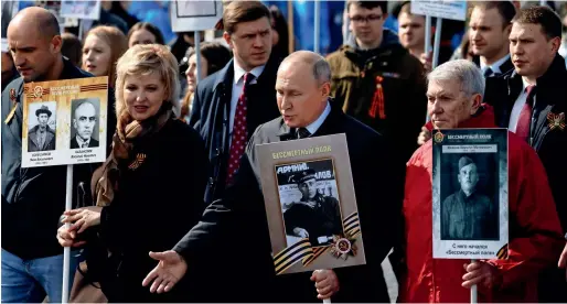  ?? ?? Russian President Vladimir Putin holds a portrait of his father, war veteran Vladimir Spiridonov­ich Putin, as he takes part in the Immortal Regiment march on Victory Day, which marks the 77th anniversar­y of the victory over Nazi Germany in World War II, in central Moscow on Monday. — reuters