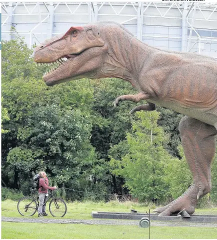  ??  ?? A man looks at a Tyrannosau­rus Rex, with St James’ Park in the background, as the Jurassic Kingdom arrives in Leazes Park, Newcastle. It will be staying until October 1