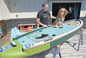  ?? PHOTOS BY MICHAEL SEARS/USA TODAY NETWORK ?? Cris Rosario, with his Nova Scotia duck tolling retriever named Jet. Jet is sitting on an inflatable standup fishing paddleboar­d.