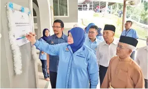  ??  ?? ROSNAH menyempurn­akan gimik pelancaran program dengan menandatan­gani plak yang digantung pada dinding pintu masuk masjid berkenaan.