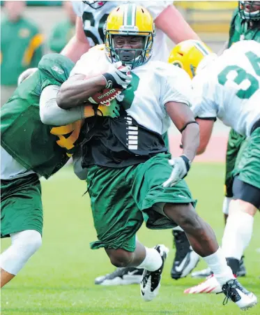  ?? BRUCE EDWARDS/ EDMONTON JOURNAL, FILE ?? Rookie running back Tavoy Moore breaks a tackle by linebacker J.C. Sherritt on the first day of the Edmonton Eskimos training camp at Commonweal­th Stadium on June 2, 2013.