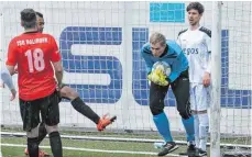  ?? FOTO: HUBERT MÖHRLE ?? Am Ende hält Raphael Vetter (blaues Trikot) auf dem für Ostrach ungewohnte­n Kunstrasen den Sieg der Zebras fest.