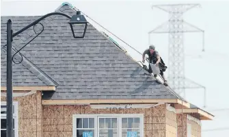  ?? SEAN KILPATRICK, CP ?? A constructi­on worker shingles the roof of a home in a new subdivisio­n in Ottawa.