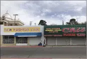  ?? SUMAN NAISHADHAM — THE ASSOCIATED PRESS ?? A woman walks past two out-of-business clothing stores located steps away from the U.S.-Mexico border in Nogales, Ariz.