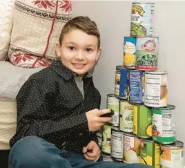  ?? BILL GREEN/THE FREDERICK NEWS-POST ?? Walkersvil­le Elementary School fourth grader Liam Kalbskopf displays the can-stacking skills that helped earn him recognitio­n from Guinness World Records for most cans stacked into a pyramid in less than 30 seconds by someone younger than 16.